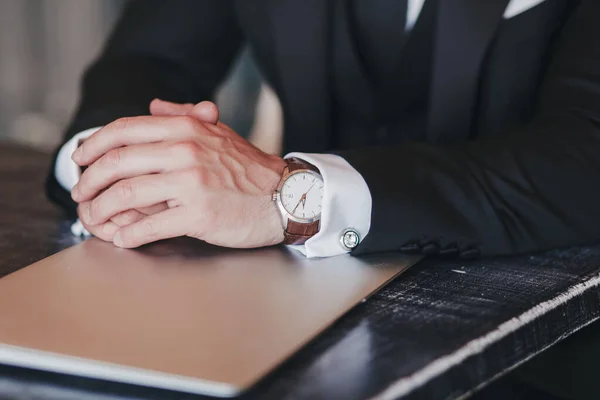 close-up of the hands of a successful man with a watch and laptop. business concept