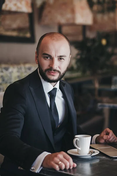 Business man in suit drinking coffee in a cafe