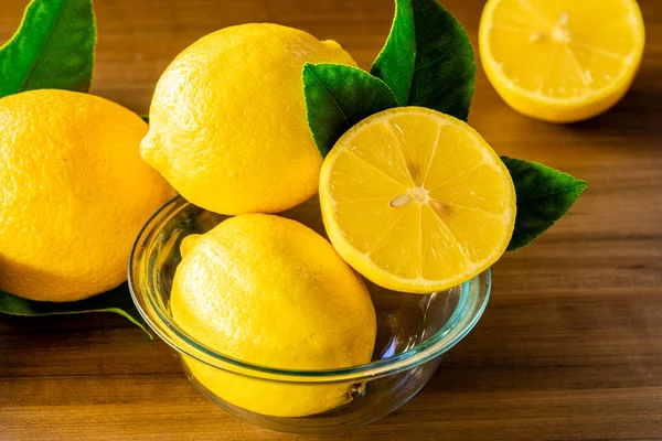 Kaseyi limonlu ve yeşil yapraklı, ahşap arka planda kapat