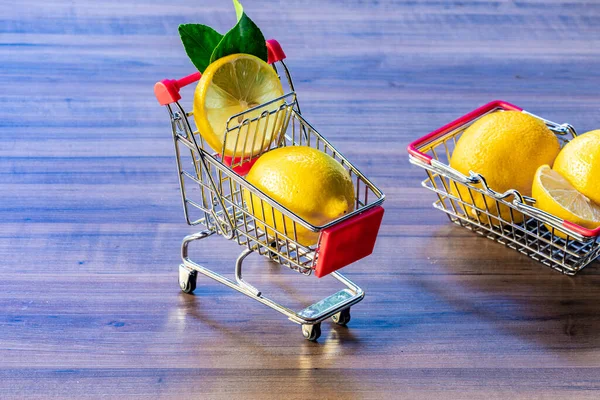 Supermarket basket and supermarket cart carrying green leaf and lemon