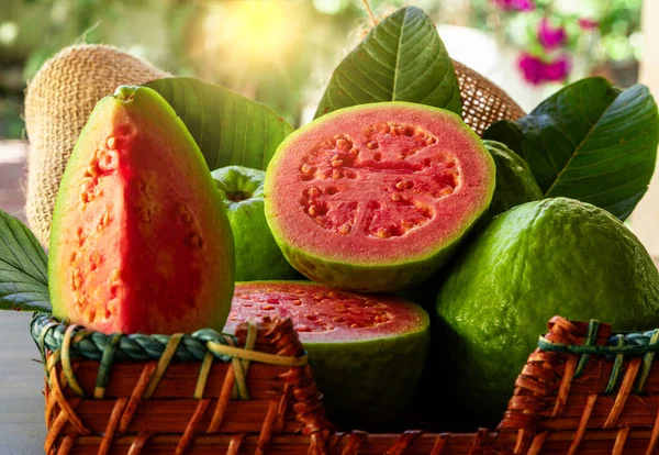 Güzel ahşap sepet, kırmızı guava ve gün batımında yeşil yapraklar..