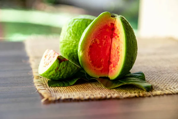Kırsal Ahşap Arka Planda Yeşil Yaprakla Dilimlenmiş Kırmızı Guava Yakın — Stok fotoğraf