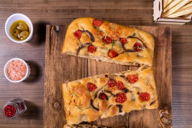Çeri domatesli, siyah zeytinli ve biberiyeli geleneksel İtalyan Focaccia.