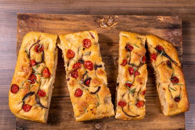 Çeri domatesli, siyah zeytinli ve biberiyeli geleneksel İtalyan Focaccia.