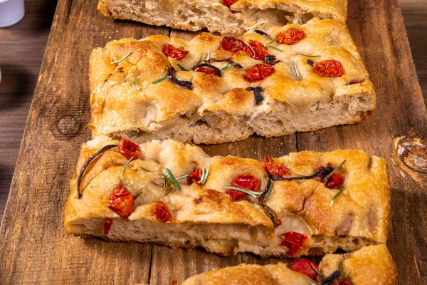 Çeri domatesli, siyah zeytinli ve biberiyeli geleneksel İtalyan Focaccia.