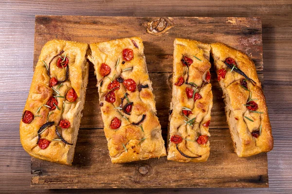 Çeri domatesli, siyah zeytinli ve biberiyeli geleneksel İtalyan Focaccia.