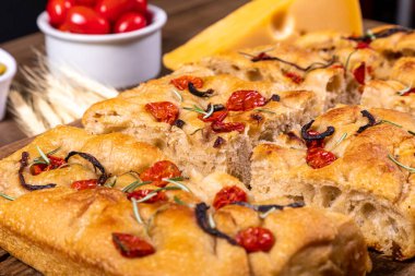 Çeri domatesli, siyah zeytinli ve biberiyeli geleneksel İtalyan Focaccia.