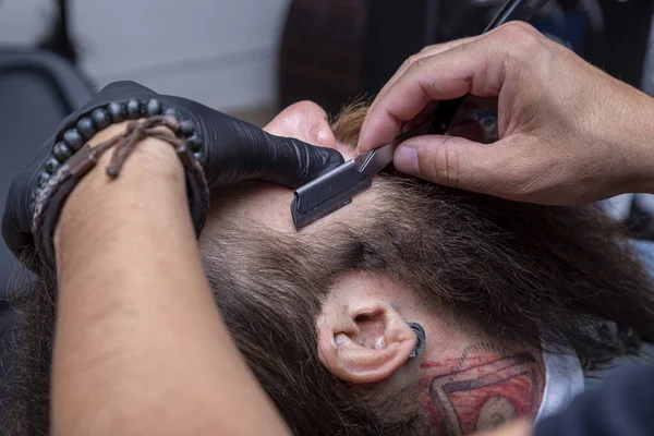 理发师用剃须刀在理发店切男人的红胡子 — 图库照片