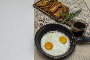 Kırsal bir demir tavada kızarmış yumurta, tahtanın üstünde tost ve kahvaltıda bir fincan kahve.