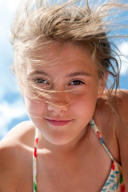 Düşük açılı görünümü güzel gülümseyen oynak kız portre portre mavi gökyüzü arka plan ile. Canlı yaz dikey görüntü.