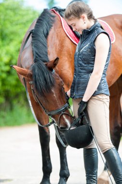 Onun güzel meraklı komik kırmızı atı ile genç oldukça genç bayan binicilik. Renkli yaz aylarında açık havada dikey görüntü.