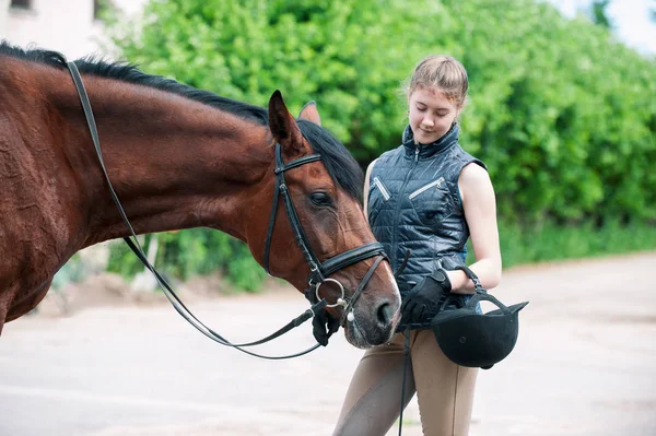 Junges Teenager-Mädchen schaut zärtlich auf ihr Lieblings-rotes Pferd — Stockfoto