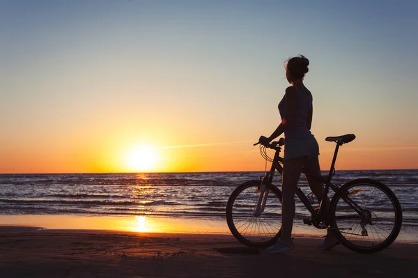 Sportowa kobieta rowerzysta sylwetka na wielokolorowe zachód słońca oświetlenie tła — Zdjęcie stockowe