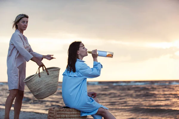 İki genç kadın sahilde birlikte şarap içme eğleniyor — Stok fotoğraf