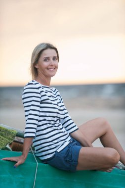 Yaz günbatımı sunligh plajda oturan çekici genç kadın