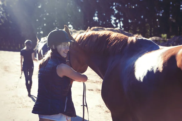 太陽光線で彼女の茶色の馬を導く若い 10 代の少女乗馬 — ストック写真