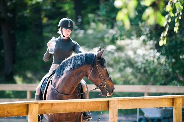 Joven chica bonita descansando después de montar a caballo de entrenamiento en son — Foto de Stock