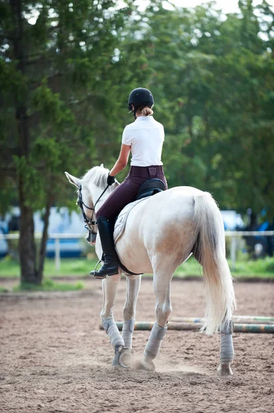 Young teenage girl equestrian practicing horseback riding on man — Stock Photo, Image