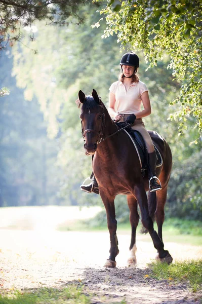 Young girl riding horseback at early morning in sunlight — Stock Photo, Image