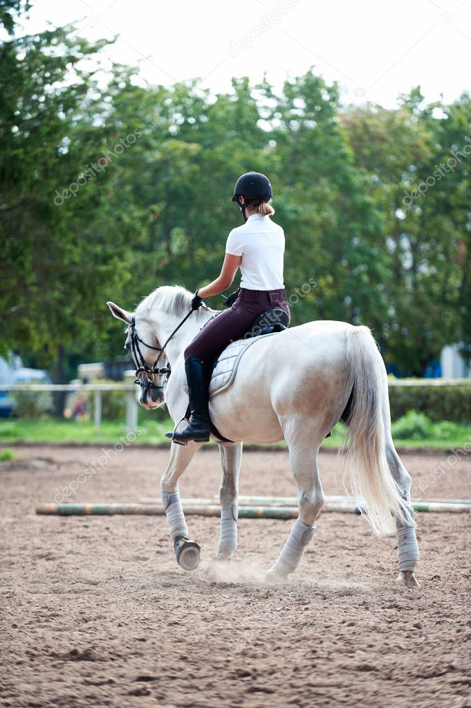 Young teenage girl equestrian practicing horseback riding on man