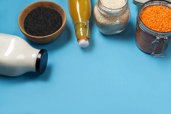 Beyaz ve siyah susam tohumlarının çeşitli çeşitleri turuncu mercimek çekirdekleri cam kavanozlar içinde tahta bir tabakta bambu kaşığı, üst manzara. Sıfır atık.
