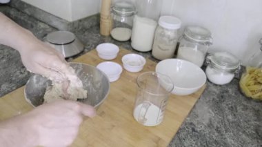 Tanınmayan bir adam ekmek hamuru yoğurup tuz ekliyor. Ev yapımı ekmek kavramı.