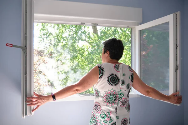 Kadın nefes almak için pencereyi açıyor. Karantina konsepti.