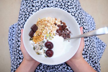 Mısır gevreği, yoğurt, meyve kasesi olan tanınmamış bir kadın. Sağlıklı beslenme, yaşam konsepti.
