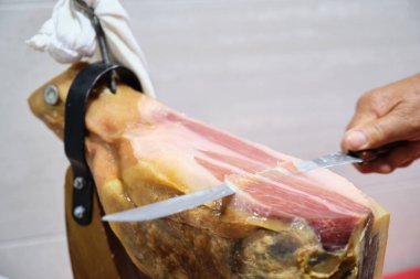 Kıdemli adam jambon bıçağıyla İberya jambonu kesiyor. İspanyol gastronomi kavramı.