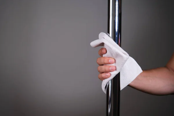 Hand cleaning a metallic pole with a cloth. Cleaning concept.