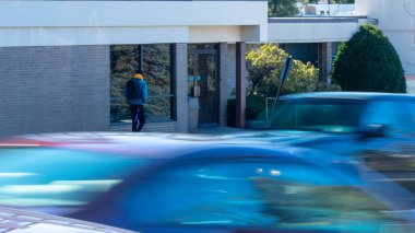 Meşgul bir caddenin karşısındaki işe yaklaşan bir arabayla gelen bir adam.