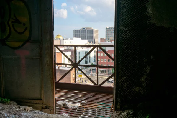 街のスカイラインの古い放棄された建物のオープンドアを見る — ストック写真