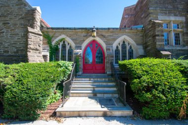 Her iki tarafında budanmış çalılar olan kaldırım taşı kilisesinin kırmızı kapısına giden adımlar.