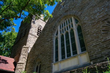 Pennsylvania 'nın varoşlarında bir kaldırım taşı kilisesinde büyük lekeli bir cam pencere.