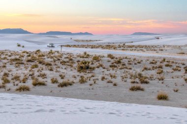 Çöl Yol Gezisi Manzara. Tek araba gün batımında sert bir çöl manzara ile New Mexico White Sands Ulusal Anıtı int uzak bir dolambaçlı yol aşağı sürücüler. Kopyalama alanı ile yatay yönlendirme.