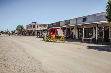 Tombstone, Arizona, USA - May 1, 2019: Stagecoach and Wild West style storefront facades on the streets of historic Tombstone. The ghost town turned tourist destination draws over 400,000 tourists annually. clipart
