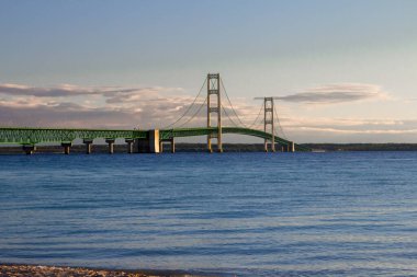 Mackinaw Köprüsü Panorama. Ön planda Michigan Gölü 'nün sakin mavi suyuyla Mackinac Köprüsü' nde sabah ışığı. Ünlü asma köprü Michigan eyaletinin Yukarı ve Aşağı Yarımadasını birbirine bağlıyor..