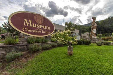 Cherokee, Kuzey Carolina, ABD - 12 Ağustos 2020: Cherokee Kızılderili Müzesi 'nin dışındaki Büyük Totem Kutbu yüz maskesi ve COVID -19' un yayılmasını yavaşlatmak için maske takıyor..
