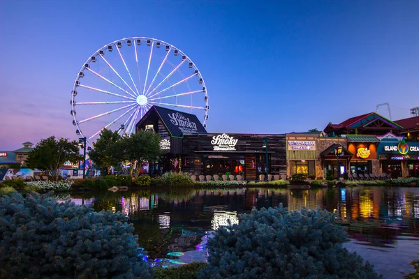 Pigeon Forge, Tennessee, ABD - 16 Ağustos 2020: Smoky Mountain Skywheel Ferris Wheel ve Ole Smoky Moonshine Distillery, Tennessee 'deki tatil beldesi Pigeon Forge' daki adanın müzik çeşmelerine yansıdı.. 