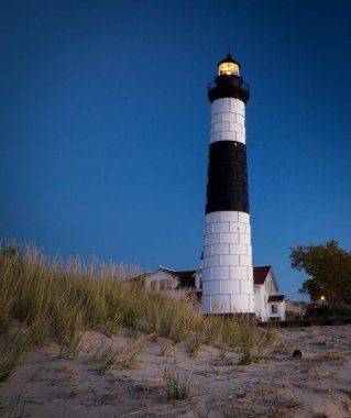 Aydınlatılmış Deniz Feneri Feneri Arkaplanı dikey yönelimde. Michigan Gölü kıyısındaki Big Samur Feneri, Michigan eyaletinin Ludington Eyalet Parkı 'nda yer almaktadır.. 