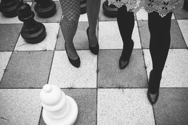 Women standing on bricks with chess board pattern. — Stock Photo, Image