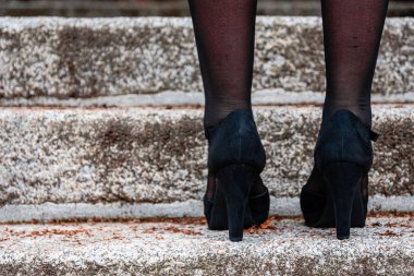 Yüksek topuklu siyah ayakkabı giyen bir kadının ayakları