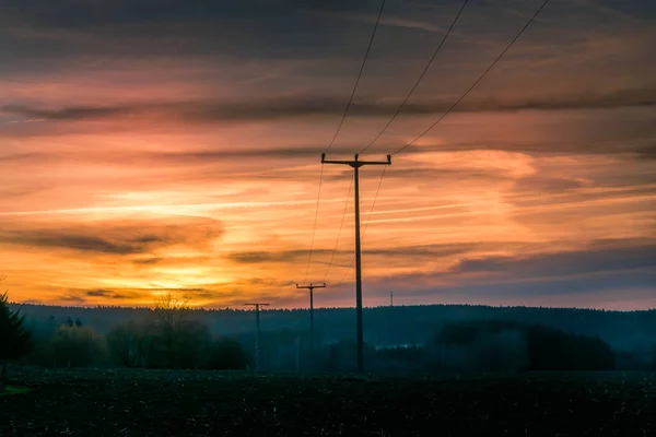 Apus de soare portocaliu colorat cu stâlpi siluetați — Fotografie, imagine de stoc