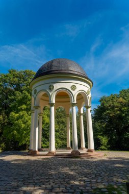 Zarif kemerleri ve kubbeli çatısı olan büyüleyici bir bahçe köşkü, ziyaretçileri canlı yeşil ağaçlar karşısında mimari güzelliğini takdir etmeye davet ediyor. Güneş ışığı bölgeyi sıcak suyla yıkar..