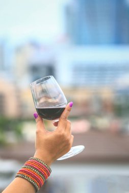 Womon kırmızı şarap gözlük günbatımı, kutlama kavramı sırasında balkonda tutan elleri yukarı Blose