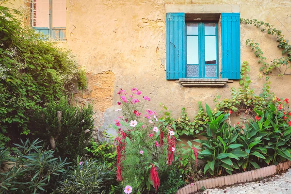 Facade of resident with blue windows and small garden in a small town, France