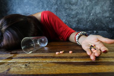 Aşırı dozda ilaç alan ve tahta masada yatan kadın aşırı doz ve intihar konsepti.