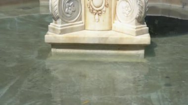 Çeşmenin tabanına yakın plan, neredeyse hiç su akmadığı zaman. Güneşli bir günde çekilmiş. Suyun üzerinde güzel bir parıltı