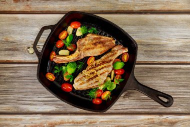 Ahşap zeminde ızgara domuz bifteği ve demir tava. Üst görünüm.