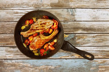 Domatesli kızarmış biftek ve ahşap arka planda tavada sarımsak..